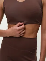 Top deportivo negro con espalda nadadora, copas removibles y detalle de logo sutil en el elástico inferior.