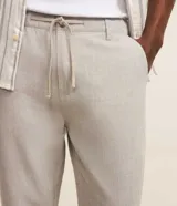 Pantalón masculino relaxed fit confeccionado en oxford de algodón, color beige, con trabillas en la cintura y cordón ajustable con lazo. Cuenta con bolsillos delanteros y traseros.