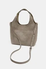 Bolso mini shopper de piel color gris topo, con doble asa de mano y asa bandolera extraíble. Cuenta con bolsillo interior con cremallera y cierre mediante botón imantado.