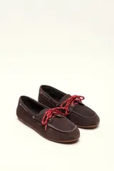 Mocasín tipo boat shoe color marrón, confeccionado en cuero, con cordones de cuero marrón y cordones decorativos azules.