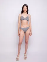 Conjunto de bikini estampado con motivos geométricos en tonos celeste y naranja. El corpiño es de corte triangular con breteles finos regulables y copas desmontables. La bombacha es de corte clásico.