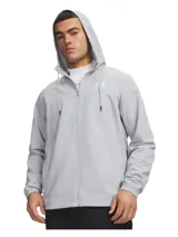 Campera Under Armour tipo cortavientos color gris, con capucha ajustable con cordones, cierre frontal completo y bolsillos laterales con cierre. Incluye forro de malla y puños elásticos.
