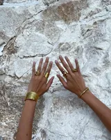 Brazalete rígido abierto de bronce con textura irregular.