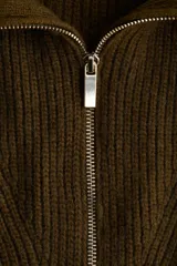 Buzo de punto acanalado en color verde oscuro, con cuello elevado y cierre frontal parcial. Presenta diseño de hombros caídos y terminaciones acanaladas en puños y bajo.