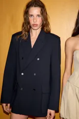 Blazer oversize de corte recto con cuello solapa y cierre frontal cruzado con botones. Presenta mangas largas con hombreras, trabillas en los hombros y grandes bolsillos de plastrón con solapa en el delantero. Incluye abertura en la espalda y forro interior.