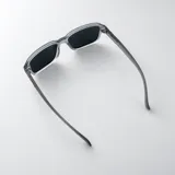 Lentes de sol polarizados con armazón translúcido gris mate y cristales oscuros, de diseño rectangular y detalles metálicos en las patillas.