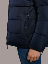 Campera puffer azul marino de Calvin Klein, de diseño acolchado con cuello alto y cierre frontal de cremallera. Incluye bolsillos laterales con cierre y chaleco interior desmontable.