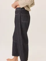 Pantalón de corte barrel en tejido de pana con estampado geométrico sutil y costuras a la vista. Presenta tiro medio, cierre frontal con botón y bolsillos laterales.