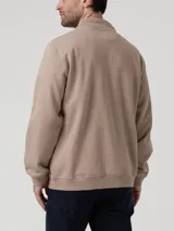 Buzo de hombre con medio cierre frontal y cuello alto, confeccionado en algodón orgánico con interior de french terry. Presenta un diseño liso en color taupe con un pequeño logo bordado en el pecho.