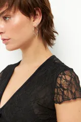 Top de encaje negro con escote en V y tiras de terciopelo. Es de manga corta y corte ajustado.