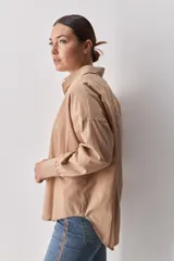 Camisa celeste de corte oversize, con mangas largas, cuello camisero y cierre frontal de botones.
