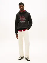 Buzo con capucha Tommy Hilfiger de color negro, con cordones ajustables y un diseño gráfico bordado en el pecho que incluye inscripciones de estilo universitario y automovilístico.