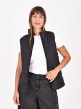 Chaleco puffer negro con cuello alto y cierre frontal.