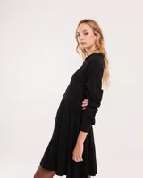 Vestido corto marrón con cuello camisero, abotonado en el frente, mangas largas con elástico en los puños y falda escalonada con volados.