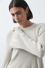 Top de tejido acanalado con sutil acabado metalizado, de silueta entallada con diseño peplum en la cintura y mangas largas levemente acampanadas.