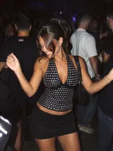 Top negro con escote halter y diseño ajustado, decorado con tachas metálicas circulares en toda la superficie frontal.