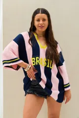 Remerón tejido de punto oversize con diseño de rayas verticales en color azul marino y rosado, cuello en V con borde amarillo y mangas largas.