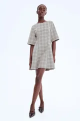 Vestido corto de sarga con estampado de cuadros, escote redondo, mangas al codo y cintura entallada con costuras visibles.