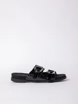 Sandalia baja negra con textura de cocodrilo (croco) en las tiras anchas. Presenta dos hebillas metálicas plateadas ajustables. La base es negra y plana.