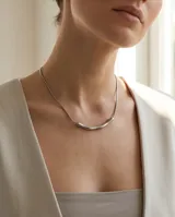 Collar de acero en tono plateado mate, compuesto por una cadena fina y una barra central con diseño curvo y minimalista.