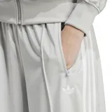 Pantalón Adidas Adicolor Classic Firebird color gris claro con tres tiras blancas a los costados, corte ancho, cintura elástica y logo bordado.