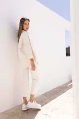 Sobre camisa color crudo, de corte recto, con cuello camisero, cierre frontal con botones y mangas largas con puños abotonados.