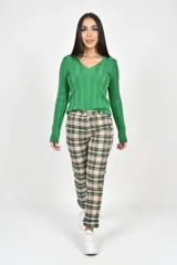 Pantalón de corte recto con estampado de cuadros escoceses en tonos beige, negro y verde. Presenta bolsillos delanteros funcionales y cierre frontal con botón.