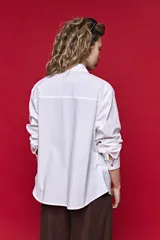 Camisa de manga larga color blanco, con cuello clásico y cierre frontal de botones de nácar. Presenta un corte cómodo y versátil.