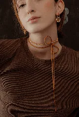 Gargantilla con tira de strass plateado y tiento de cuero marrón para atar.