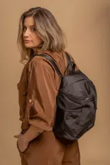 Mochila urbana de diseño compacto en color negro, confeccionada en nylon resistente. Cuenta con un compartimento principal con cierre, bolsillo frontal con cierre y correas ajustables con detalle de marca.