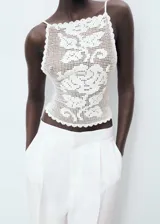 Top de crochet color blanco con diseño entallado, espalda abierta con cierre de lazo y tirantes finos.