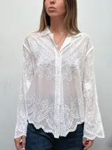 Camisa de encaje color crema con diseño floral bordado, cuello camisero, cierre frontal de botones y mangas largas con terminación acampanada.