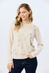 Buzo tejido de algodón color beige con cuello redondo, manga larga y delicados detalles bordados de flores.
