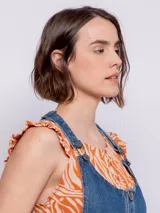 Jumper de jean azul con tiras regulables, cuatro botones metálicos, hebillas y dos bolsillos delanteros.