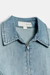 Camisa entallada de denim color celeste, con cuello solapa y cierre frontal con cremallera metálica, de manga larga.
