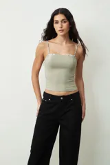 Top verde grisáceo con breteles finos y escote recto con detalle de encaje floral.