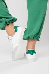 Zapatillas acordonadas de cuero color blanco con puntera de gamuza gris y detalles en verde.