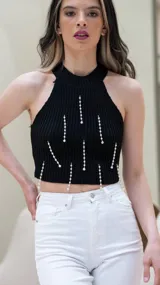 Top negro tejido con cuello halter y detalle de perlas colgantes.