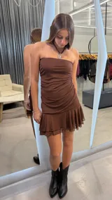 Vestido corto color chocolate, con diseño strapless y detalle de fruncido lateral. Presenta un ruedo con volado de tul que aporta volumen y movimiento.