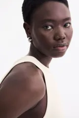 Musculosa color crema de punto acanalado, corte entallado, cuello redondo y ribete fino en escote y sisas.