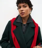 Abrigo largo de paño color verde oscuro, con solapas amplias tipo blazer, cierre frontal cruzado con botones y abertura trasera. Diseño estructurado y elegante.