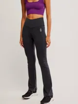 Calza de tiro alto con diseño acampanado en el ruedo, confeccionada en tejido acanalado de color negro. Presenta una costura en forma de V en la cintura y un pequeño logo bordado en la cadera.