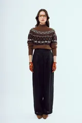 Sweater de punto color marrón, con cuello alto y diseño tejido con patrones geométricos en tonos negros y blancos en la parte superior y mangas.