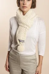 Bufanda tejida a mano en punto arroz color crudo, con detalle de pompón en uno de los extremos.