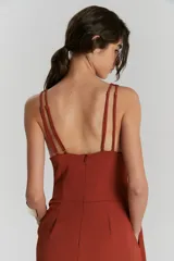 Entero color terracota con escote en V profundo y breteles anchos. La parte superior es ajustada y la parte inferior es un pantalón ancho con pliegues en la cintura.