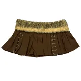 Pollera mini de tiro bajo color marrón, con diseño plisado y detalles de cordones laterales con ojales metálicos. Presenta una banda de piel sintética removible en la cintura.