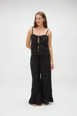 Top de pijama blanco confeccionado en algodón, con tirantes finos, escote recto y aberturas frontales con lazos ajustables.