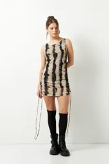 Minivestido sin mangas con estampado tie-dye en tonos beige y negro. Confeccionado en microtul con leve transparencia y cordones ajustables en los laterales.