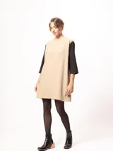 Vestido corto negro con mangas 3/4 verdes, cuello bote y bolsillos laterales.