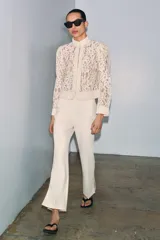 Blazer de encaje con cuello redondo, manga larga con puños y cierre frontal con botones. Presenta un diseño estructurado con bajo recto.